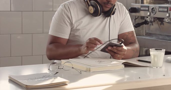 man use his smartphone then put glasses and earphones and drawing in notepad