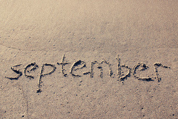 Inscription SEPTEMBER on a gentle beach sand