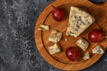 Pieces of blue cheese on wooden serving board.