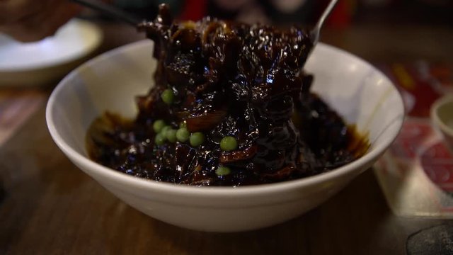 4K People eating the Jajangmyeon with chopsticks in a restaurant. Korean noodles in black bean sauce-Dan