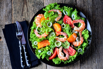 Healthy salad of red and yellow tomatoes, with shrimps, sweet onions, lettuce, balsamic vinegar and olive oil.