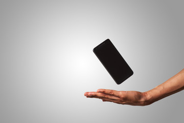 close-up of an open hand and a floating smart phone in isolated background