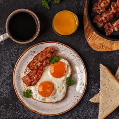 Breakfast with bacon , fried egg, coffee and orange juice.