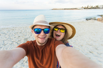 Happy traveling couple making selfie sea background , sunny summer colors, romantic mood. Stylish sunglasses, straw hat. Happy laughing emotional faces.