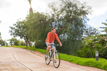 Fototapeta premium Handsome young man on bike in the park. Bicycle, leisure and people concept.