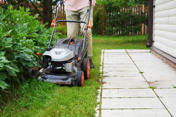 Man handling lawn with lawnmower.