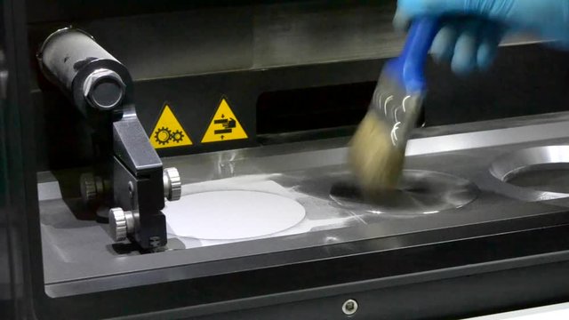 Preparing for operation of a laser sintering machine. A man with a brush removes excess metal powder from the working surface Inside the working chamber 3d of the printer printing metal