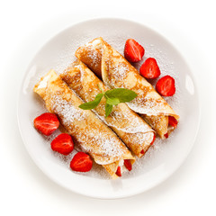 Crepes with strawberries and cream on white background