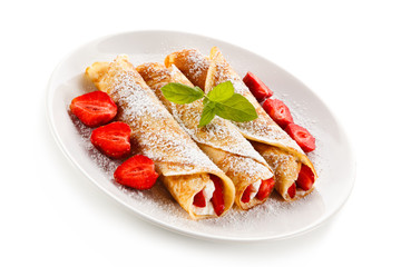 Crepes with strawberries and cream on white background