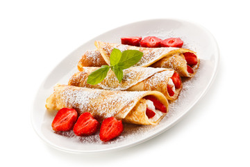 Crepes with strawberries and cream on white background