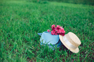Straw hat and romantic wild-flower bunch bouquet on green grass lawn. Background layout with free text space. Countryside lifestyle or summer relaxation concept.