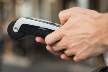 Close-up: Man`s hands are working with a debit card reader. It's a popular way to pay a bill by Hand Swiping Credit Card In Store, restaurant or café today. Get Paid Faster. Concept: demonetization. 