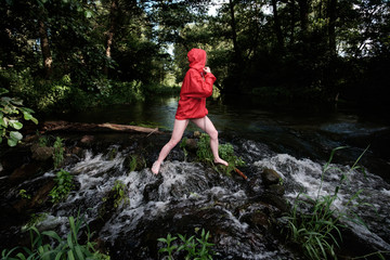 Naklejka na ściany i meble girl in red waterproof jacket fording mountain river