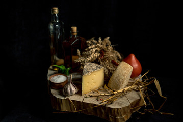 Fototapeta na wymiar Kraft homemade cheese on the dark background with vegetables with bottles on wood table