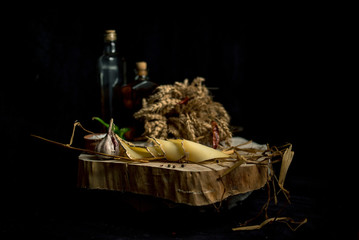 Kraft homemade cheese on the dark background with vegetables with bottles on wood table