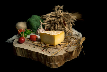 Big pieces of cheese with vegetables on a wood board 