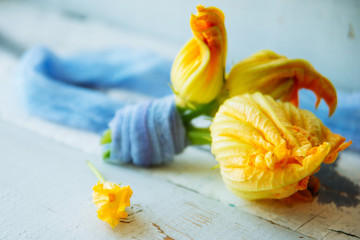Beautiful yellow pumpkin flower on a blue wooden surface