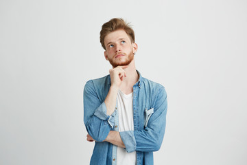 Portrait of dreamy young handsome guy thinking dreaming with hand on chin over white background.