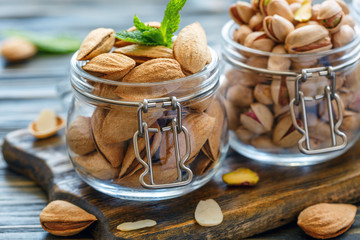 Almonds and pistachios in glass jars.