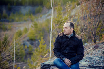 portrait of traveller brunette woman with long straight hair wearing checked shirt and jeans enjoying picturesque sitting on edge enjoying panoramic view of mountains with snow peaks and pine forests