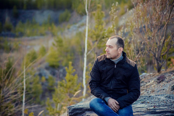 portrait of traveller brunette woman with long straight hair wearing checked shirt and jeans enjoying picturesque sitting on edge enjoying panoramic view of mountains with snow peaks and pine forests