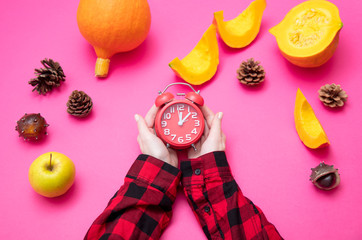 Female hands holding alarm clock with vegetables
