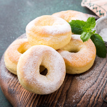 Homemade baked donuts with powdered sugar on green background. Selective focus.