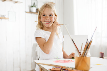 Little girl with blonde hair and freckles enjoying art wearing white t-shirt. Female child captured...