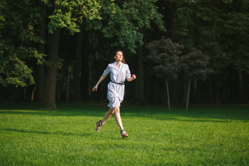 Fototapeta premium happy brunette woman run in forest green lawn at sunny day