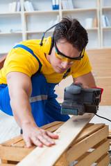 Repairman carpenter polishing a wooden board with an electric po