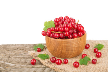 Red currant berries in wooden bowl on wooden table with white background