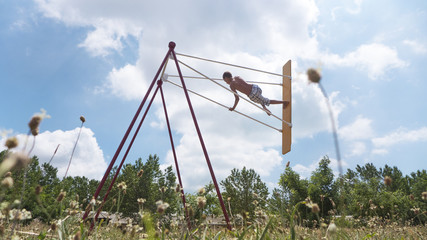 Fototapeta na wymiar Boy teenager high riding on a swing, against the sky