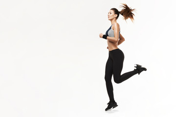 Beautiful athletic girl in sportswear training running over white background. Copy space.