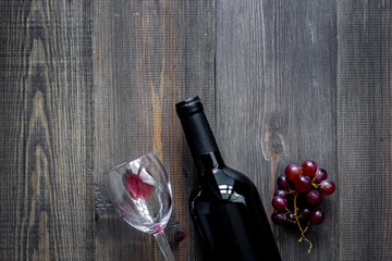 Bottle of wine and grape on dark wooden table background top view copyspace