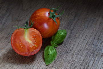 Red tomatoes with green basil leaves on wooden background