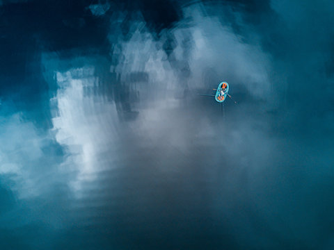 Aerial view of the lake with boat and reflecting clouds 