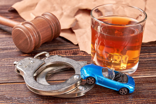 Gavel, handcuffs, car, whiskey, paper. Booze driving concept.