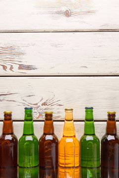 Vertical image group of bottles. Several bottles with beer on light wooden background.