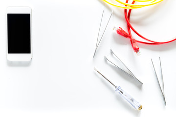 Daignostic of gadgets. Cell phone, wires and tools on white background top view copyspace