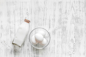 Farm dairy products. Milk, eggs on light wooden background top view copyspace