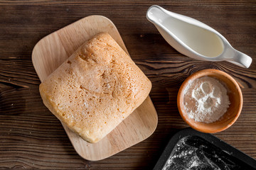 Make bread. Loaf and ingredients on dark wooden table background top view