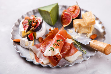 Cheese plate with thyme, a board. A different cheese with fresh figs Honey, walnut almonds and meat. Snack jamon, prosciutto, camembert, parmesan, brie green cheese with basil.selective focus.