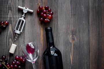 Open wine. Bottle and corkscrew on dark wooden table background top view copyspace