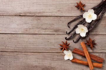 Vanilla sticks with cinnamon and flower on a old wooden background with copy space for your text. Top view