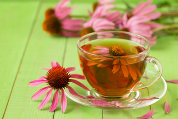 Cup of echinacea tea on green wooden table