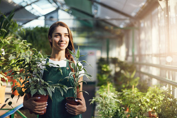 Female greenhouse store employee holding plants ready for sale