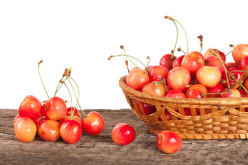 Yellow cherry in a wicker basket on a wooden table with a white background