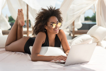 Cheery youthful woman recreating with gadget on resort