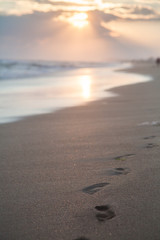 footprints on sandy beach at sunset
