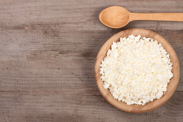 Cottage cheese in a wooden bowl on old wooden background with copy space for your text. Top view